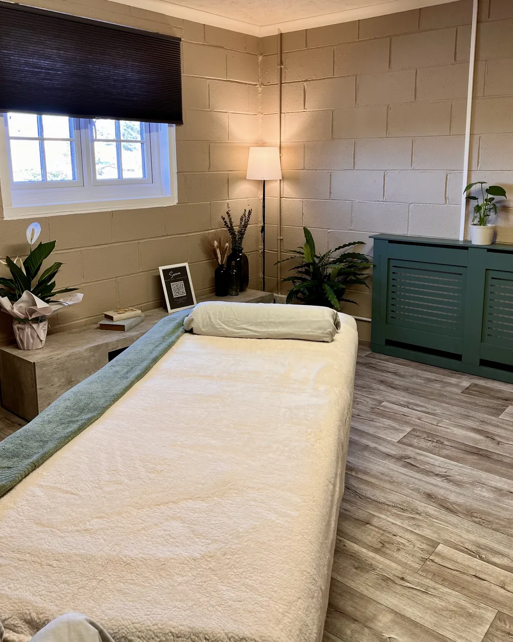 Our treatment room, with a made-up couch, plants and a warm lamp