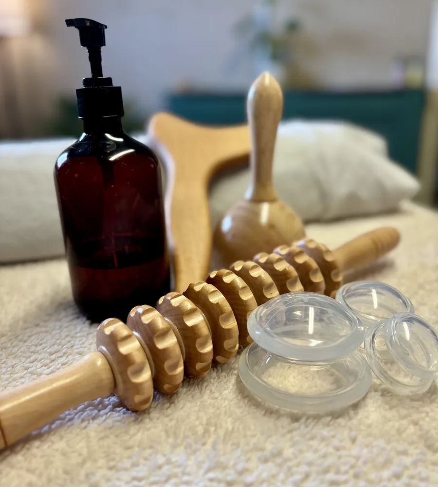 Wood therapy tools, cups and oil laid out on a towel